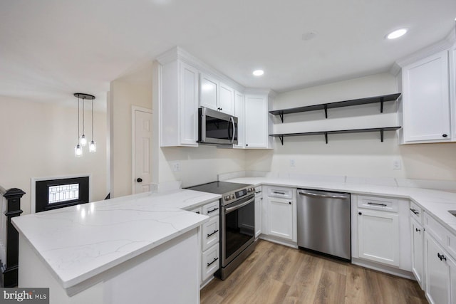 kitchen with white cabinetry, appliances with stainless steel finishes, kitchen peninsula, pendant lighting, and light hardwood / wood-style floors