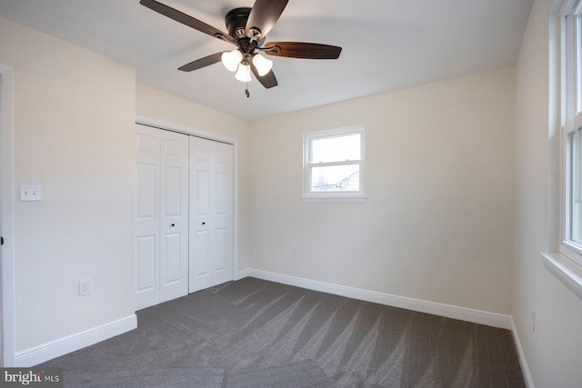 unfurnished bedroom with dark colored carpet, ceiling fan, and a closet