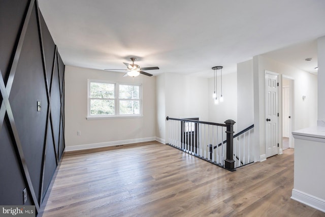 empty room with ceiling fan and light hardwood / wood-style flooring