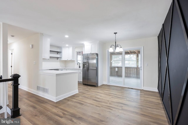 kitchen with sink, light hardwood / wood-style flooring, stainless steel refrigerator with ice dispenser, a notable chandelier, and white cabinets