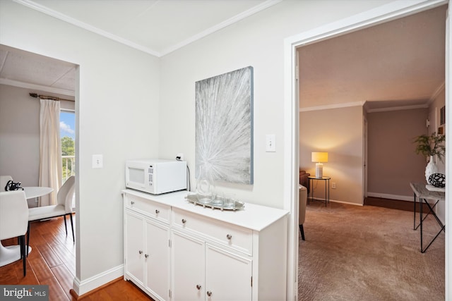 kitchen with white cabinetry, crown molding, and light wood-type flooring