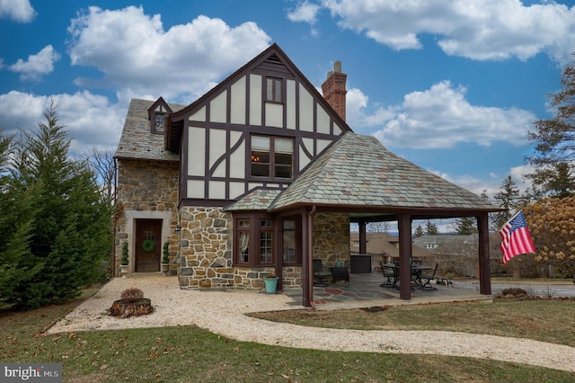 back of property featuring a fire pit, a yard, and a patio