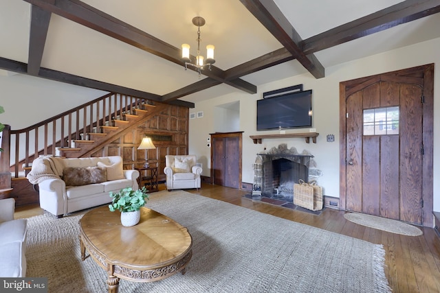 living room featuring beamed ceiling, a tile fireplace, an inviting chandelier, and dark hardwood / wood-style flooring