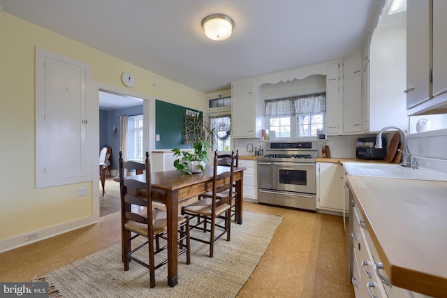 kitchen featuring white cabinetry, double oven range, a wealth of natural light, and sink