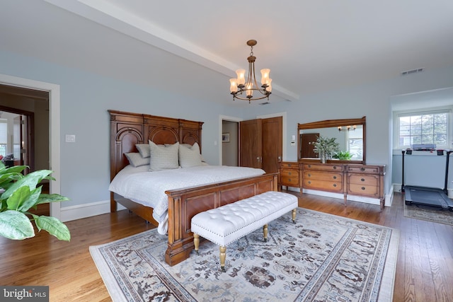 bedroom with hardwood / wood-style floors and a notable chandelier