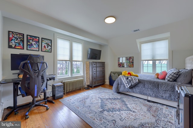 bedroom with wood-type flooring and radiator heating unit