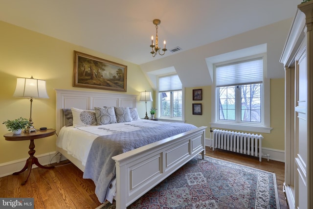 bedroom with an inviting chandelier, wood-type flooring, and radiator