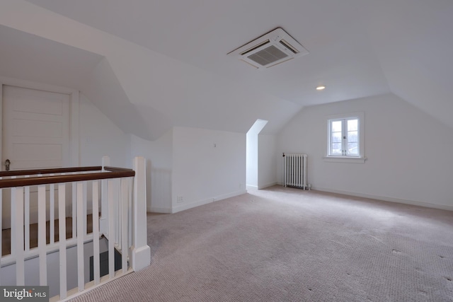 bonus room with lofted ceiling, radiator heating unit, and light colored carpet