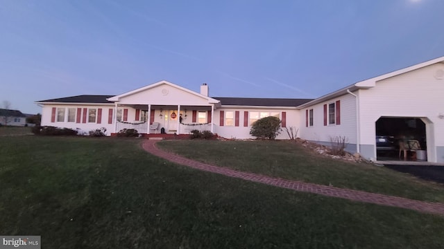 ranch-style house featuring a yard, a garage, and covered porch