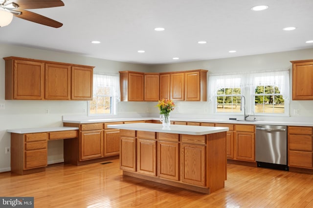 kitchen with built in desk, sink, a center island, stainless steel dishwasher, and light hardwood / wood-style floors