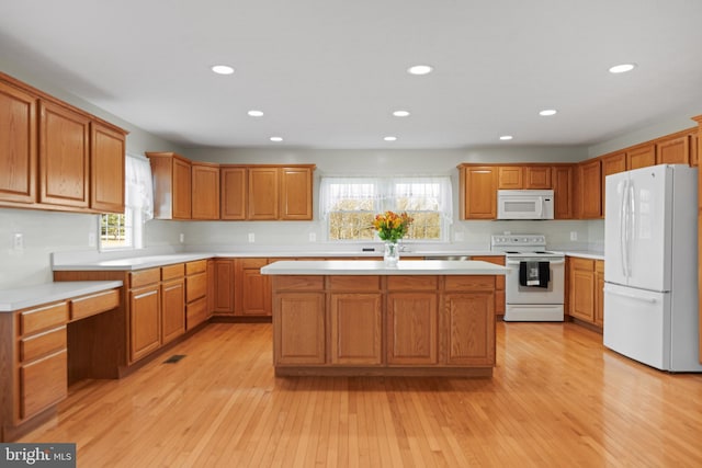 kitchen featuring a center island, light wood-type flooring, and white appliances