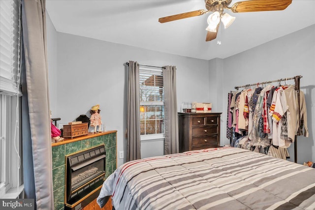 bedroom with ceiling fan and a tile fireplace