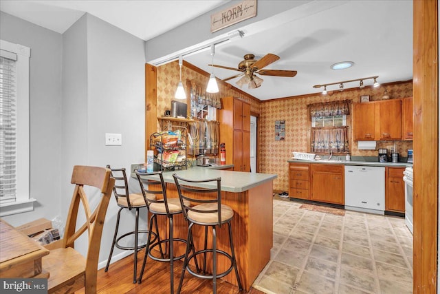 kitchen featuring dishwasher, sink, a kitchen bar, ceiling fan, and kitchen peninsula