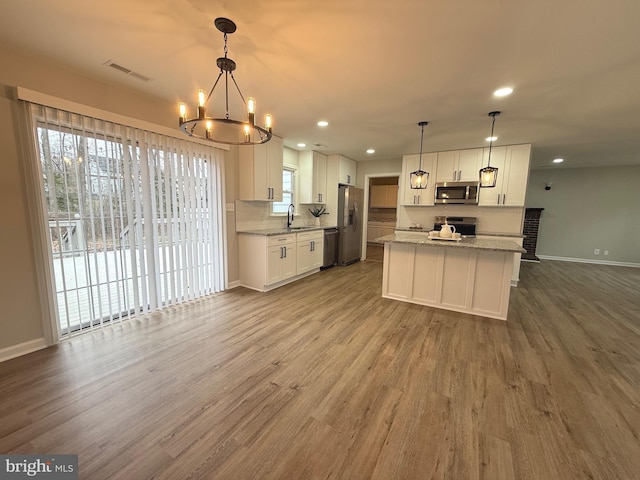 kitchen featuring white cabinetry, hanging light fixtures, stainless steel appliances, and sink