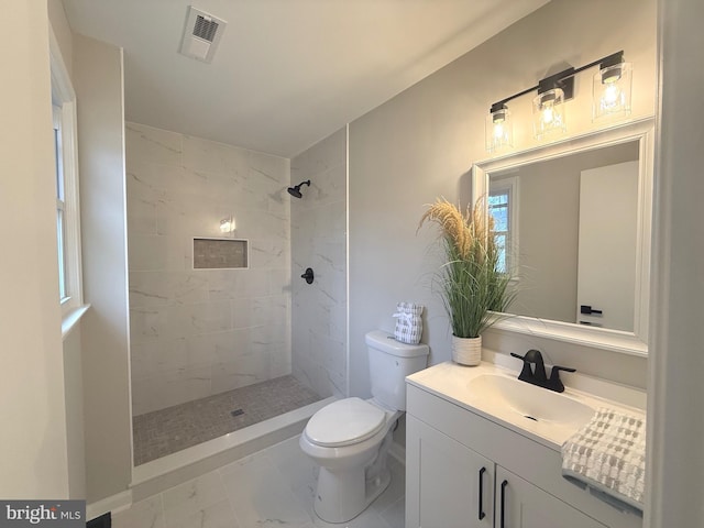 bathroom featuring tiled shower, vanity, and toilet