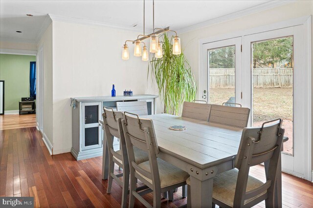 dining area featuring baseboards, hardwood / wood-style floors, and crown molding