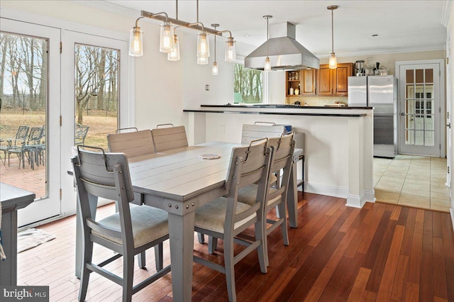 dining space with a healthy amount of sunlight, light wood-style flooring, and crown molding