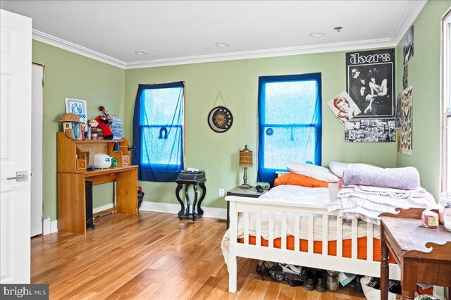 bedroom with ornamental molding, multiple windows, baseboards, and wood finished floors