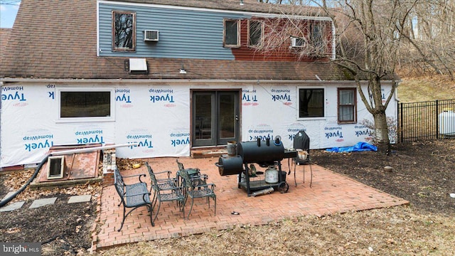 back of property featuring an AC wall unit, roof with shingles, and fence