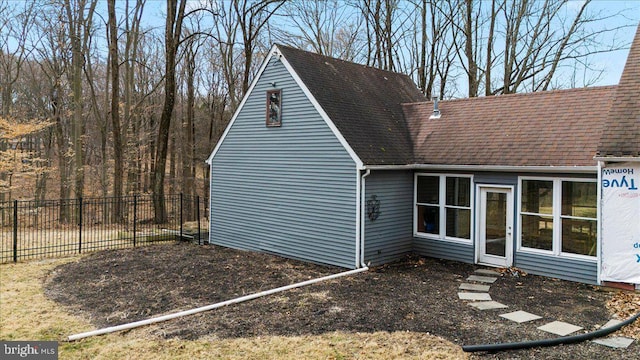 exterior space featuring a shingled roof and fence