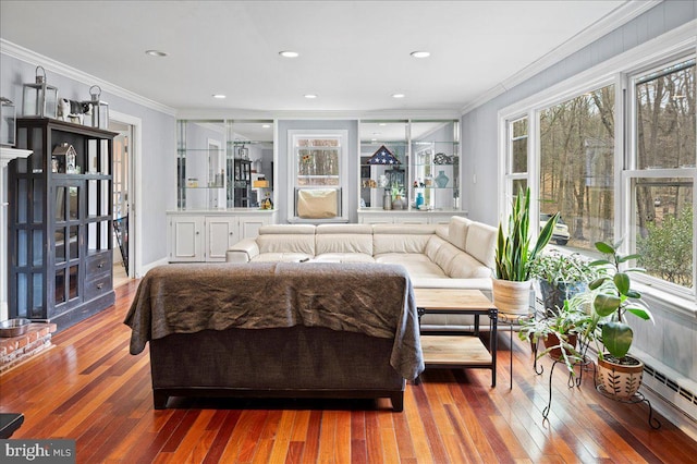 bedroom with hardwood / wood-style floors, multiple windows, baseboard heating, and crown molding