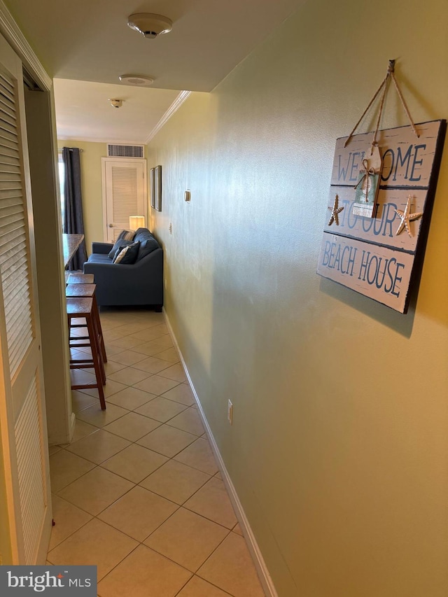 corridor featuring light tile patterned floors and ornamental molding