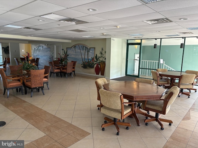 dining area with a drop ceiling, light tile patterned floors, and a wall of windows