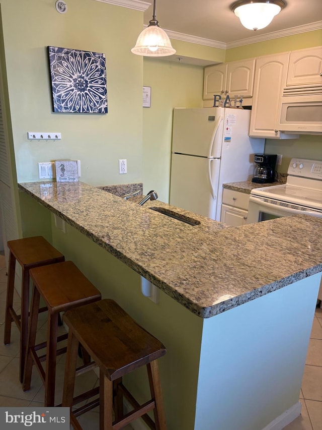 kitchen featuring a breakfast bar, sink, white cabinetry, kitchen peninsula, and white appliances