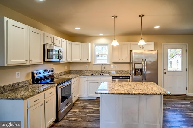 kitchen featuring stainless steel appliances, white cabinetry, a center island, and sink