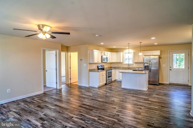 kitchen with stainless steel appliances, white cabinetry, a center island, and decorative light fixtures