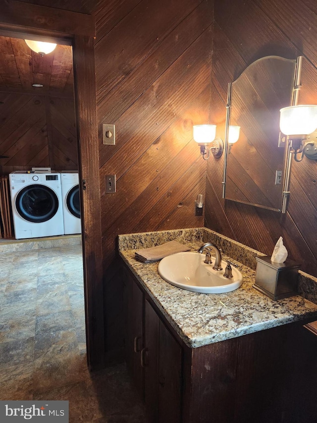 bathroom featuring vanity, washer and dryer, and wood walls