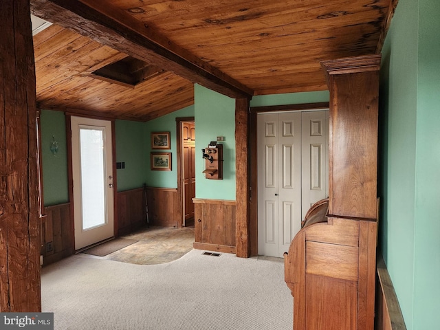 foyer entrance with light colored carpet, lofted ceiling with beams, wooden ceiling, and wooden walls