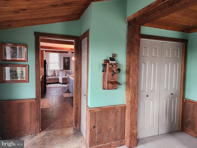 corridor featuring lofted ceiling, wooden walls, and wooden ceiling