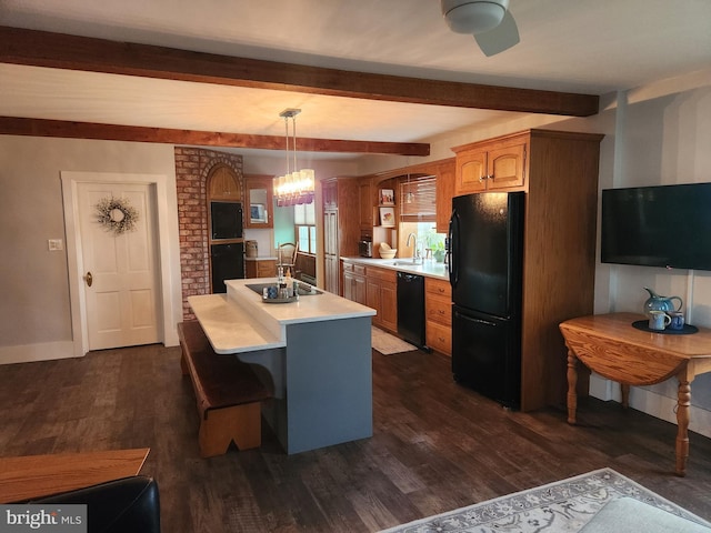 kitchen with dark wood-type flooring, sink, an island with sink, pendant lighting, and black appliances