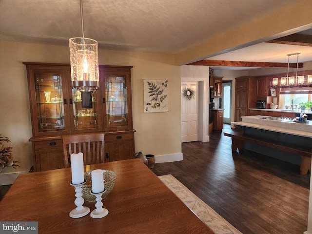 dining room with a notable chandelier, beam ceiling, and dark wood-type flooring