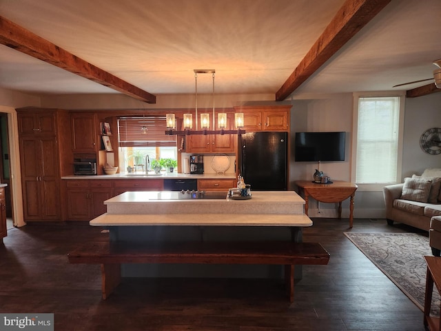 kitchen featuring beamed ceiling, sink, hanging light fixtures, a center island, and black appliances