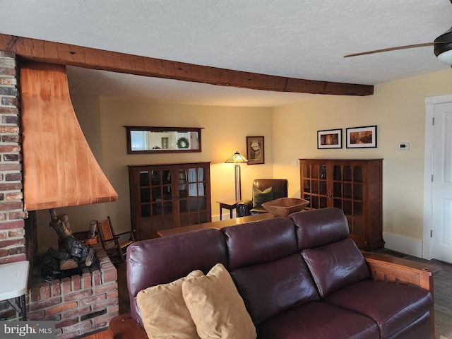 living room featuring beamed ceiling, ceiling fan, and a textured ceiling