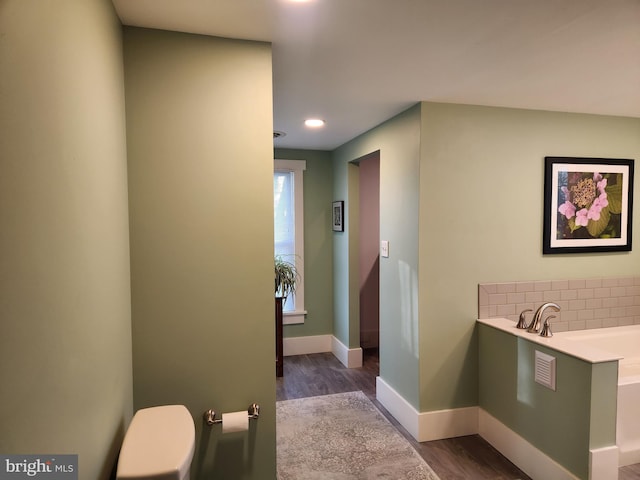 bathroom with a bathtub, decorative backsplash, and hardwood / wood-style flooring