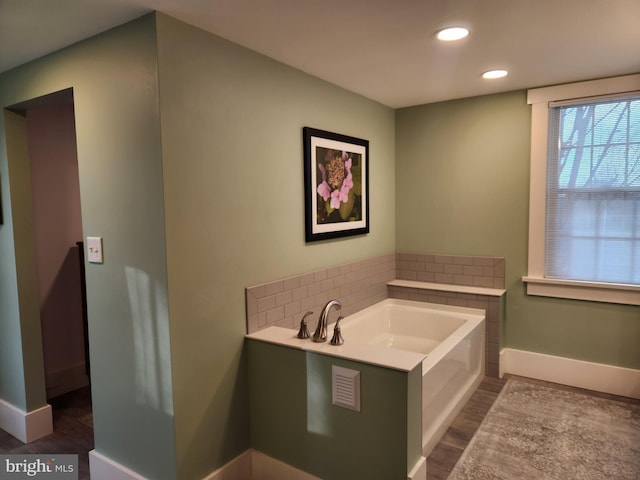 bathroom with hardwood / wood-style floors, tasteful backsplash, and a washtub