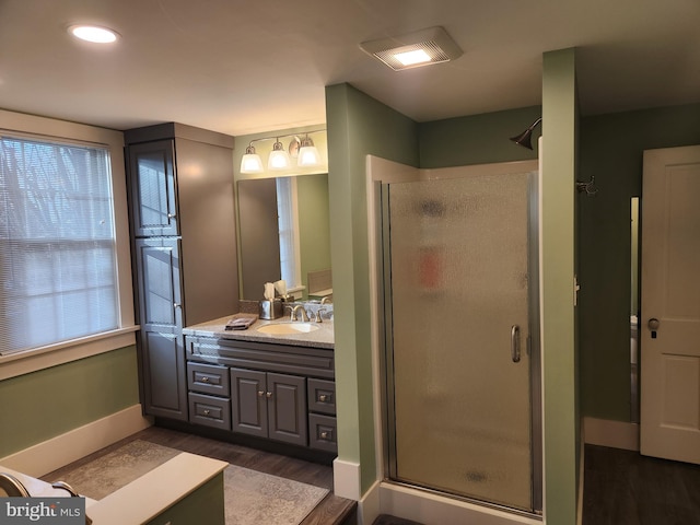 bathroom with wood-type flooring, a shower with shower door, and vanity