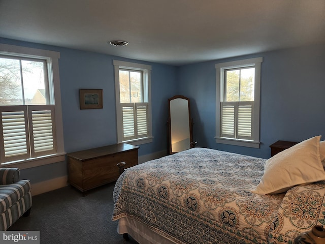 bedroom featuring dark carpet and multiple windows