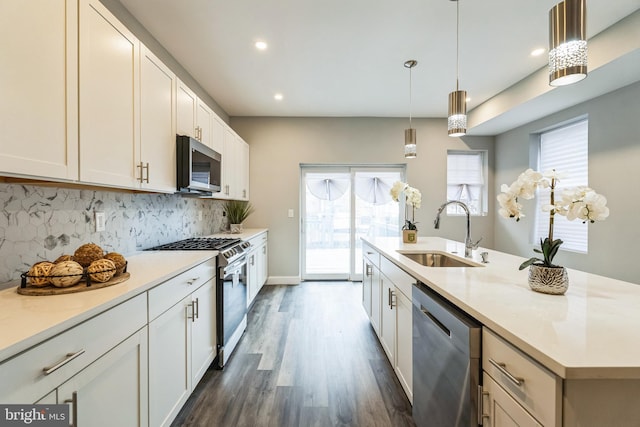 kitchen featuring sink, a center island with sink, hanging light fixtures, appliances with stainless steel finishes, and backsplash