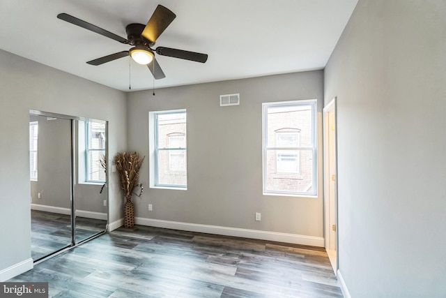 unfurnished bedroom featuring dark wood-type flooring, ceiling fan, and a closet