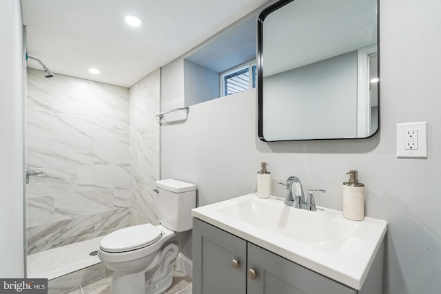 bathroom with tiled shower, vanity, and toilet