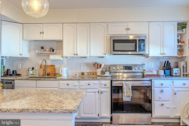 kitchen with stainless steel appliances, light stone countertops, sink, and white cabinets