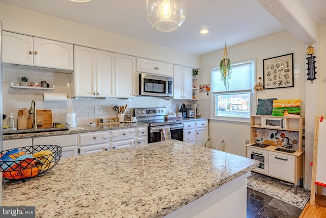 kitchen featuring sink, white cabinetry, backsplash, stainless steel appliances, and light stone countertops