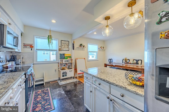 kitchen with appliances with stainless steel finishes, pendant lighting, white cabinets, and light stone counters