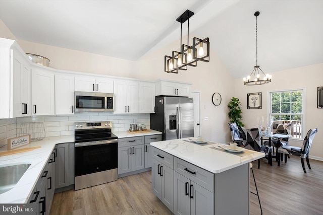 kitchen featuring stainless steel appliances, a center island, hanging light fixtures, and white cabinets