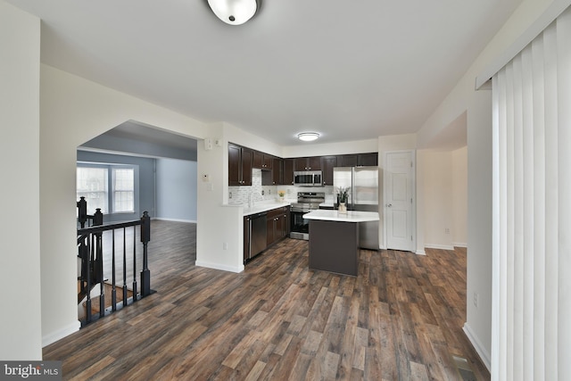 kitchen featuring dark hardwood / wood-style floors, tasteful backsplash, a center island, stainless steel appliances, and dark brown cabinets