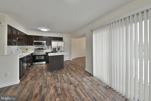 kitchen featuring dark hardwood / wood-style flooring, decorative backsplash, stainless steel appliances, and a center island